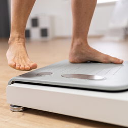 Nackte Füße eines Manns beim Betreten einer Bioimpedanz Waage