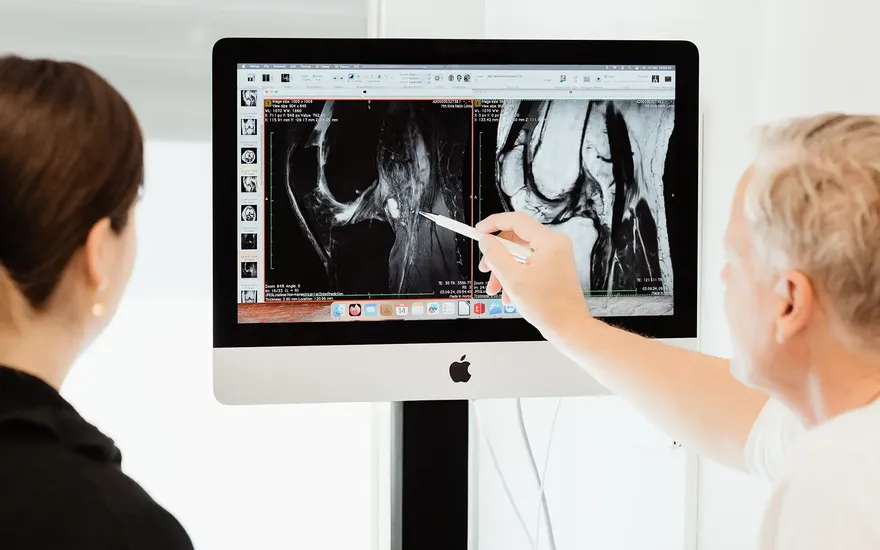 Dr. Burkhard Schubert betrachtet gemeinsam mit einer Patientin die MRT Aufnahme eines Knies am Computer