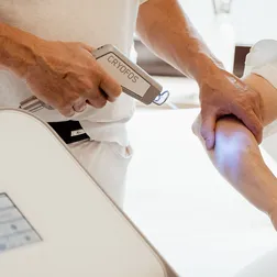 Dr. Burkhard Schubert kühlt mit dem Cryfos Gerät den Unterarm einer Patientin